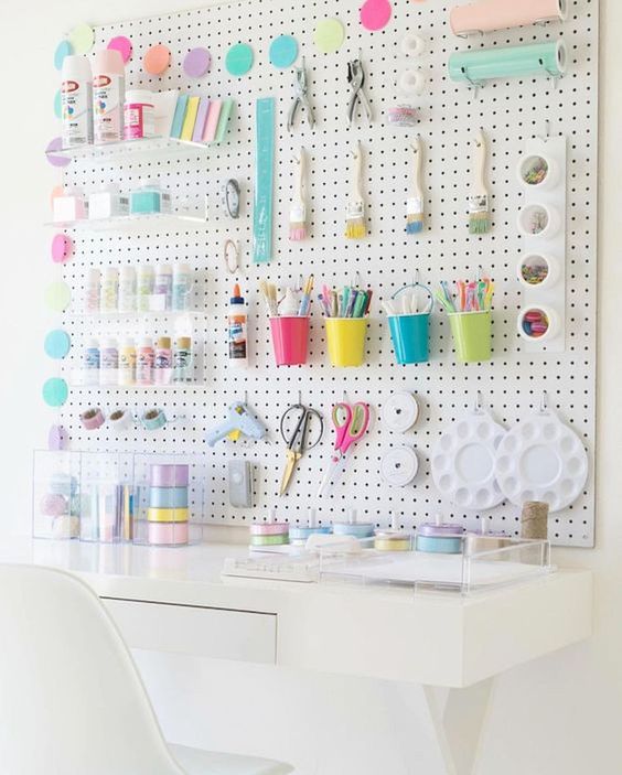 a pegboard spruced up with colorful cups, containers, hooks, acrylic ledges and other stuff