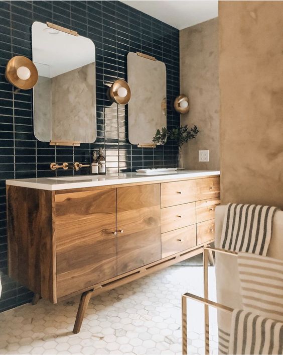 a refined mid-century modern bathroom with ran plaster walls, a wooden vanity, marble hex tiles and a navy skinny tile wall plus brass touches