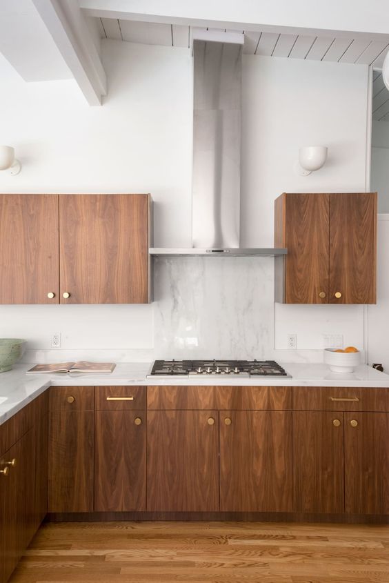 a rich-stained wood mid-century modern kitchen with white countertops, a white stone backsplash