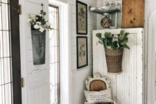a shabby chic entryway with a dresser, potted greenery and blooms, a whitewashed chair, artworks