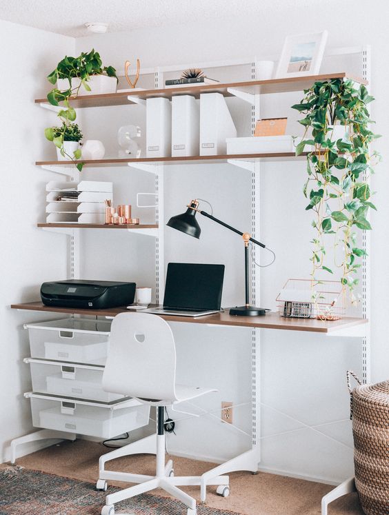 A wall mounted shelving unit with lots of shelves and boxes for storage plus a built in desk