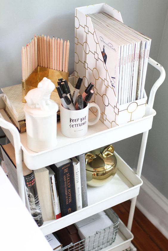 A white cart used for storage and organization   files, pens, books and pencils in a holder is a cool and mobile piece