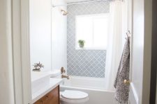 an airy mid-century modern bathroom with grey Moroccan tiles, white marble ones, a wooden vanity and touches of brass