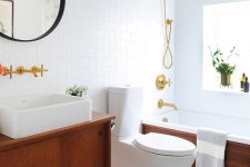 an elegant mid-century modern bathroom with white penny and subway tiles, rich stained furniture, black and gold touches