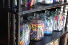 an open storage unit with large jars that are great to store crayons and markers