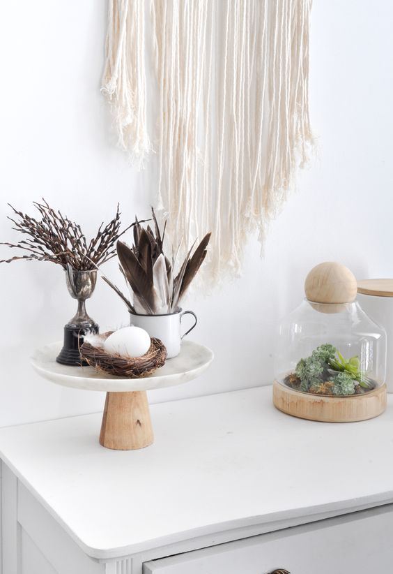 Scandinavian boho decor with a stand with a fake nest and egg, feathers and willow plus moss in a jar