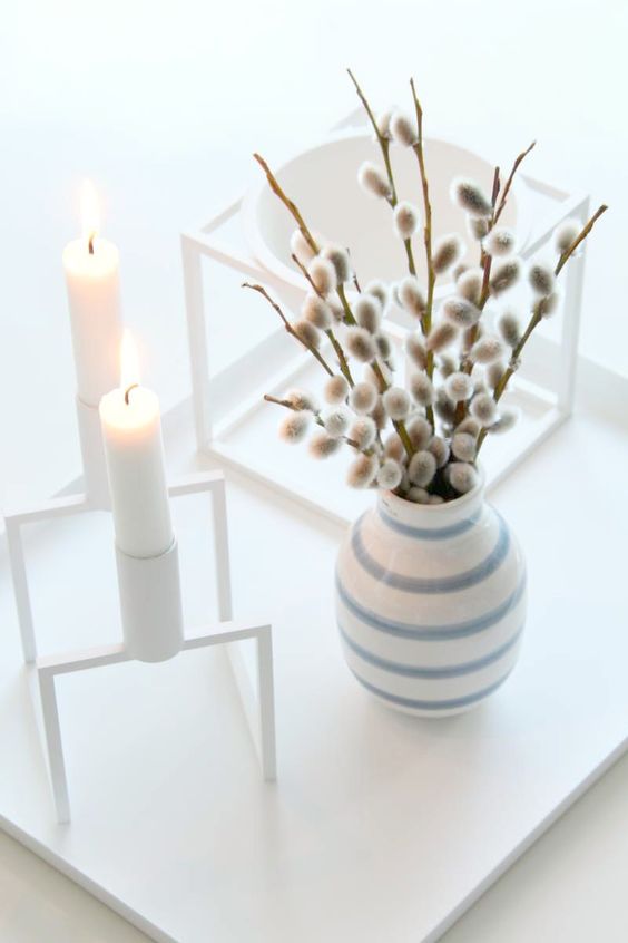 a Scandinavian spring decoration with a framed candleholder, a striped vase with willow and a bowl