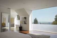 a contemporary bedroom with a laconic interior and a panoramic window with partial frosting to keep it more private
