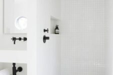 a contemporary white bathroom clad with square tiles and black fixtures, a niche shelf, a wall-mounted vanity is stylish