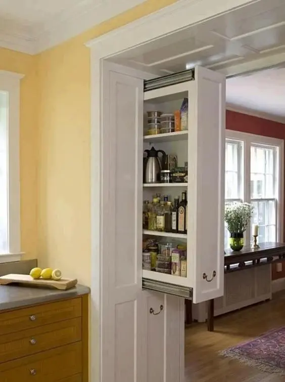 a doorway in the kitchen with hidden drawers built-in is a very cool idea to declutter the room and organize a small pantry right here