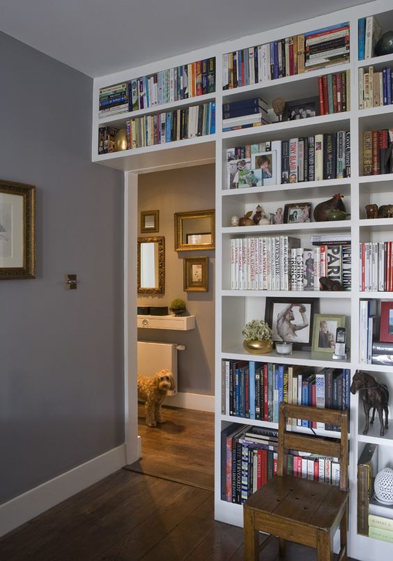 a doorway wall covered with open shelves that contain lots of books is a cool idea to organize your home library without wasting a lot of space