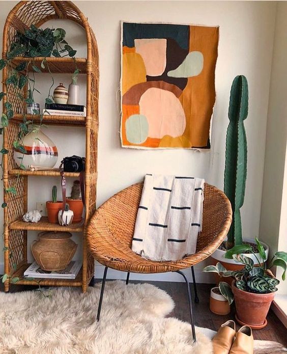 A mid century modern nook with a wicker arched shelving unit, a round wicker chair, potted plants and a cactus, bold art and rugs