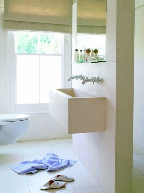 a minimalist neutral bathroom with partly frosted windows that keep it private but still bring much light inside