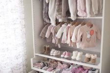 a small and cute closet with baby’s clothes on hangers, drawers and a glass drawer with compartments to organize
