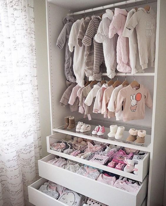a small and cute closet with baby's clothes on hangers, drawers and a glass drawer with compartments to organize
