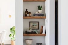 a small awkward nook by the doorway taken by niche shelves with various cool accessories and plants is a great idea to rock