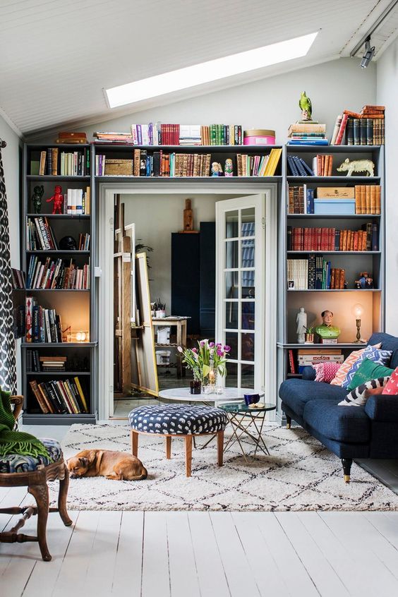 a small living room with open shelves taking a whole wall with the door - a smart idea that allows to store a lot of things here