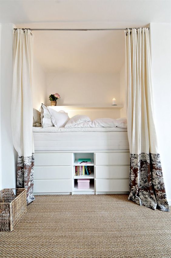 a tall bed built of several layers of drawers and open storage ocmpartments is a cozy and functional unit