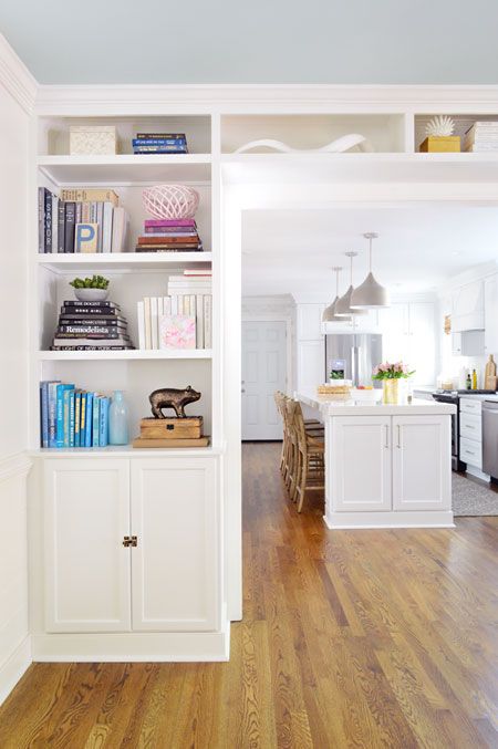a wide doorway surrounded by open shelves and cabinets is a cool idea to store a lot of things and declutter your spaces