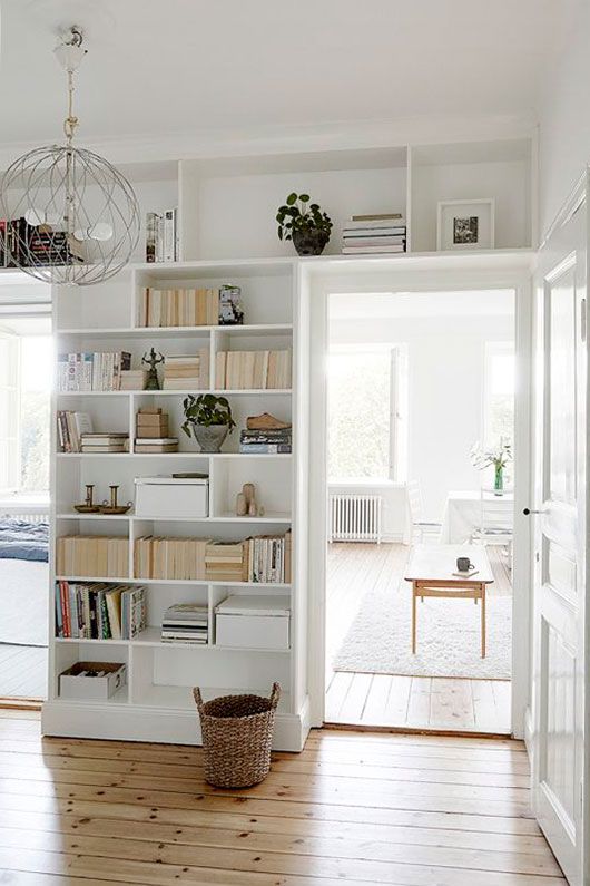 doorways with open shelves taking the wall and the space over them is a cool idea to store books and potted plants is a cool idea