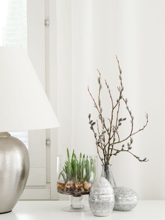 easy Scandinavian spring decor with patterned eggs, a glass with bulbs and willow in a vase