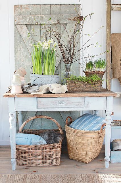 rustic Scandinavian spring decor with a wooden plaque, potted bulbs and greenery, blooming branches and linens