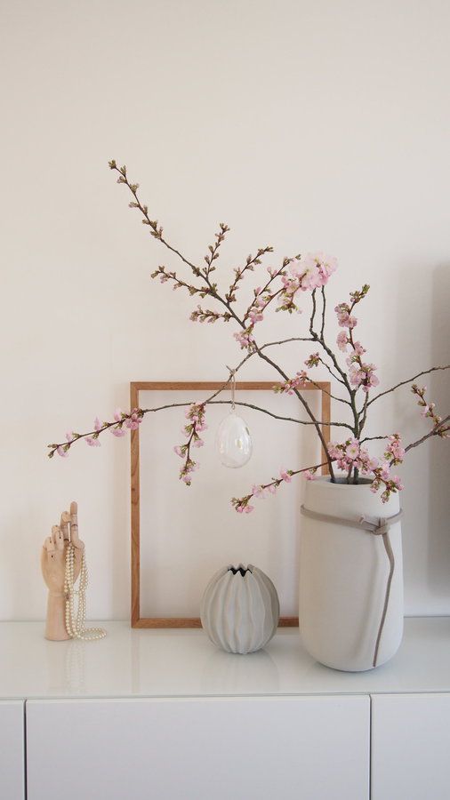 simple Nordic spring decor wiht a decorative vase and a large concrete one with blooms plus a sheer egg