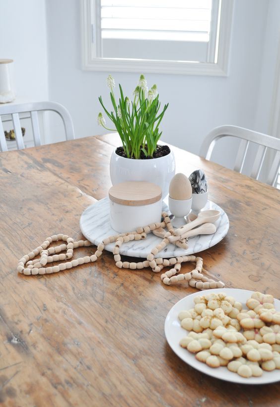 simple Nordic spring decor with an egg-shaped planter with bulbs, eggs in egg stands and wooden beads for Easter