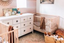 a boho desert nursery with a watercolor wall, neutral and white furniture, a desert artwork, Moroccan leather ottomans