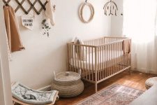 a boho gender neutral nursery with light stained furniture, a boho rug, a mobile and a littel rocker