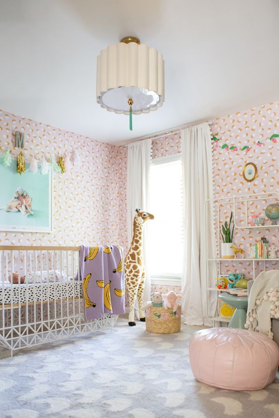a bright and fun tropical nursery with pink floral wallpaper, white furniture, pink and purple touches and fun toys