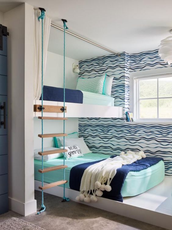 A bright seaside inspired shared boy bedroom with an accent wall, a bunk bed, a ladder and bright bedding