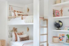 a chic neutral kids’ bedroom with a bunk bed with a wooden ladder, built-in shelves and a drawer, cool printed textiles