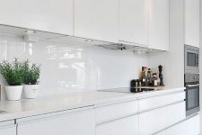 a clear white kitchen with a white glass backsplash and stone countertops is a lovely idea for a Scandinavian space