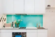 a contrasting kitchen with sleek white cabinets and a super bold blue glass backsplash that brings interest to the space