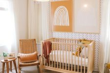 a cozy and warm-colored nursery with a printed wall, wooden furniture, a fun rug and bold art on the wall