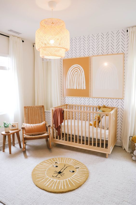 A cozy and warm colored nursery with a printed wall, wooden furniture, a fun rug and bold art on the wall