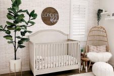 a cozy modern nursery with wallpaper walls, a sign, wicker chairs and a lampshade, potted greenery