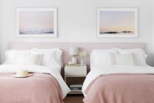 a dreamy shared girls’ bedroom with a pink headboard and beds with white and pink bedding, white leather poufs and a nightstand, ocean prints
