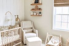 a farmhouse neutral nursery with light-colored furniture, a boho rug, a woven lamp and wooden furniture
