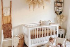 a gender neutral nursery done in warm neutrals, with white and neutral furniture, pampas grass, toys and layered rugs
