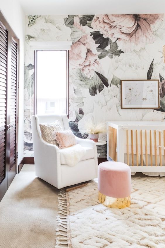 a glam and cute girlish nursery with a floral accent wall, white furniture and a pink ottoman plus a shutter wardrobe is cool