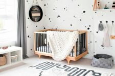 a gorgeous contemporary nursery done in black and white, with star print wallpaper, a printed rug, neutral furniture