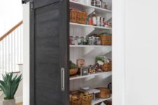 a grey sliding barn door hides the pantry and saves the space very well