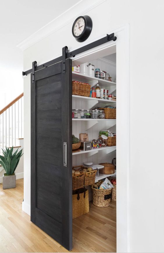 a grey sliding barn door hides the pantry and saves the space very well