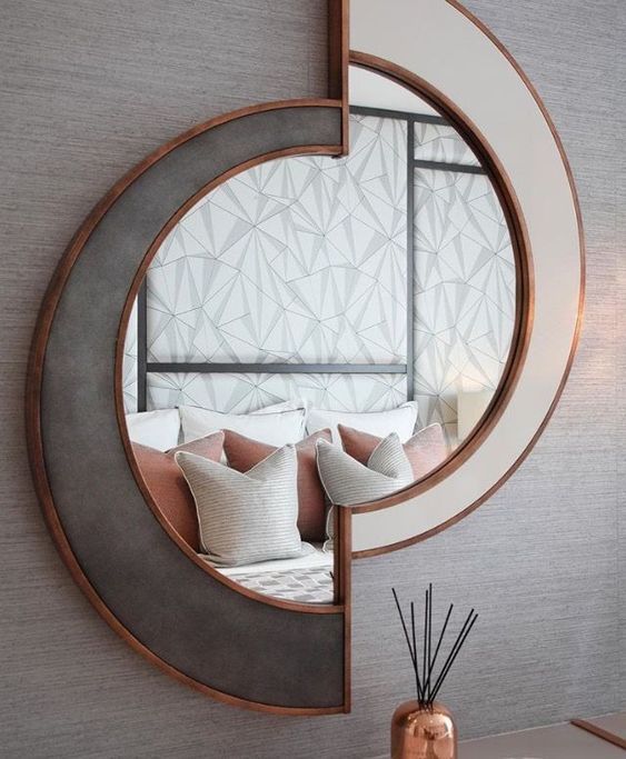 a mirror with a unique shape, it seems to be cut in two and moved, with a creamy and grey frame and copper edges