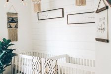 a neutral boho nursery with neutral furniture, printed linens, artworks and crochet chandeliers, a statement plant and touches of rattan