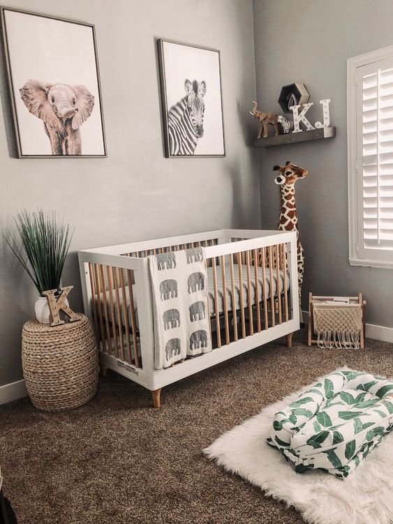 a neutral jungle-themed nursery with wooden furniture, layered rugs, an open shelf and a gallery wall