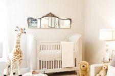 a neutral nursery with a refined crib, white furniture, a vintage mirror and layered rugs plus chic toys