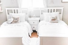 a neutral shared girls’ bedroom with white beds and a nightstand, white curtains and bedding is a very airy and dreamy idea
